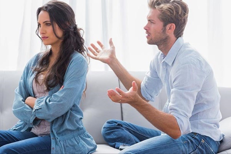 یک خانم و یک آقا با دلخوری روی مبل نشسته‌اند. خانم دست به سینه نشسته و به روبرو نگاه می کند و آقا درحال صحبت کردن دست‌های خود را باز نگه داشته و به سمت خانم نگاه می کند.